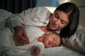 happy mother looking with her infant baby sleeping on bed at night Royalty Free Stock Photo