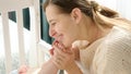 Happy mother looking at her little baby son in bed and kissing tiny feet. Concept of parenting, family happiness and Royalty Free Stock Photo