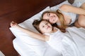 Happy mother lying in bed with little jocund daughter. Royalty Free Stock Photo