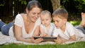 Happy mother with older and baby son browsing internet in park on tablet computer. Parenting, family, children Royalty Free Stock Photo