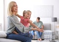 Happy mother playing with her daughter while father and son using laptop at home Royalty Free Stock Photo