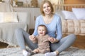 Happy mother playing with her laughing baby, sitting on floor Royalty Free Stock Photo