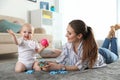 Happy mother playing with little baby on floor