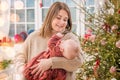 A happy mother plays with a baby in her arms at home not against the background of a decorated room and a Christmas tree Royalty Free Stock Photo