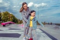 Happy mother plays with her child little boy of 3-5 years old, in autumn summer in city, skateboard training, happy Royalty Free Stock Photo