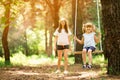 Happy mother pushing laughing daughter on swing in a park