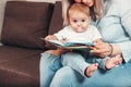 Happy mother read a book to child girl indoors sitting on the couch Royalty Free Stock Photo