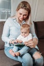 Happy mother read a book to child girl indoors sitting on couch Royalty Free Stock Photo