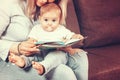 Happy mother read a book to child girl indoors sitting on the couch Royalty Free Stock Photo