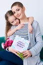 Happy Mother`s Day background. Cute little girl hugging mom after giving her mothers day card. Royalty Free Stock Photo