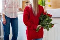 Happy Mother`s Day or Birthday Background. Adorable young girl surprising her mom with bouquet of red roses. Family celebration.