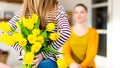 Happy Mother`s Day or Birthday Background. Adorable young girl surprising her mom with bouquet of yellow tulips.