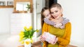 Happy Mother`s Day or Birthday Background. Adorable young girl surprising her mom, young cancer patient, with bouquet and present.