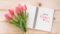 Happy MotherÃ¢â¬â¢s Day celebration greeting on white note book page background with tulip flower gift for mom on wood Royalty Free Stock Photo