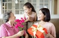 Happy mother`s day  . Child and  mother congratulating grandmother  giving her flowers and  gift box Royalty Free Stock Photo