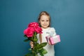 Happy mother day! Child congratulating mom. Daughter smiling and holding flowers and gift on blue background Royalty Free Stock Photo