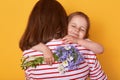 Happy Mother`s day! Child daughter congratulates mom and gives her flowers. Mum and little girl hugging, charming kid closes eyes Royalty Free Stock Photo