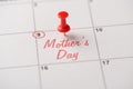 Happy mother`s day concept. Cropped close up view photo of red pushpin attached to calendar with inscription mother`s day