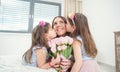 Happy mother`s day concept. Little daughters twins kiss their mother with a tulip bouquet