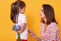 Happy mother`s day! Cute child girl congratulates her mother on holiday and wants to give flowers. Doughter hides bouquet of blue Royalty Free Stock Photo