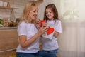 Happy mother`s day! Daughter Gives mom a gift box and a card with a heart at home on the background of the kitchen. Mum and girl Royalty Free Stock Photo