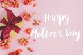 Happy mother`s day greeting card. Happy mothers day text and gift box with red flowers on pink background flat lay. Stylish flora Royalty Free Stock Photo