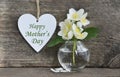 Happy Mother`s Day greeting card with jasmine spring flowers in a glass vase and decorative heart with text. Royalty Free Stock Photo