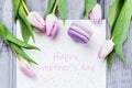 Happy mother`s day greeting card. Tulips and violet macaron on a gray wooden background