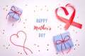 Happy Mother`s Day greeting card with red hearts, blue gift boxes and golden confetti on pastel table top, overhead shot. Royalty Free Stock Photo