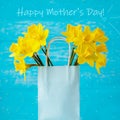 Happy mother`s day greeting card. Spring yellow daffodils in a gift bag on a turquoise background Royalty Free Stock Photo