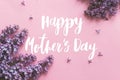 Happy mother`s day greeting card. Happy mother`s day text and lilac flowers on pink paper flat lay. Stylish floral greetings. Royalty Free Stock Photo