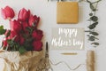 Happy mother`s day greeting card. Happy mother`s day text on card and red tulips, gift, pencil, scissors, twine on white wood, Royalty Free Stock Photo