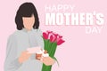 Happy Mother`s day greeting card. Woman holding greeting card, tulips and gift box on pink background and Happy Mothers day text. Royalty Free Stock Photo