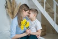 Happy mother`s day! little son gives flowers to mom, boy congratulates mom, flowers in the hands of a boy, yellow daffodils, happy