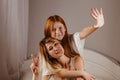 Happy mother`s day. Mom and her daughter are playing girl, smiling and hugging in bed. Family holidays and togetherness