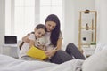 Happy Mother`s Day. Mother and daughter are reading a book while sitting on the bed at home. Royalty Free Stock Photo