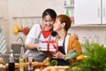 Happy mother`s day! teenager daughter congratulates mother and gives a gift in kitchen at home, birthday or celebration