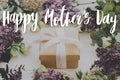 Happy mother`s day. Happy mother`s day text and gift box, lilac, roses flowers on white wood. Stylish floral greeting card. Royalty Free Stock Photo