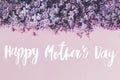 Happy Mother`s day text and lilac flowers border on pink paper, stylish floral flat lay. Happy mothers day greeting card