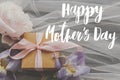 Happy mother`s day. Happy mother`s day text and peony and iris flowers and gift box on soft fabric on dark wood. Stylish floral Royalty Free Stock Photo