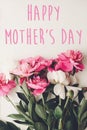 Happy mother`s day text on pink peonies bouquet on rustic white