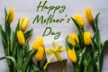 Happy mother`s day. Text sign, gift box with yellow tulips on white rustic wooden background. Greeting card with flowers concept. Royalty Free Stock Photo