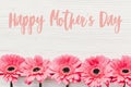 Happy Mother`s Day text sign at pink gerbera on white wooden background, flat lay. Floral greeting card. Mothers day. Pink Royalty Free Stock Photo