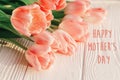 Happy mother`s day text sign on pink tulips on white rustic wood