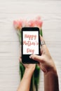 Happy mother`s day text sign on screen of phone. hand holding ga Royalty Free Stock Photo