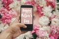 Happy Mother`s Day text sign on screen phone in hand at stylish pink and white peonies on pastel pink paper, flat lay. Stylish Royalty Free Stock Photo