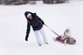 Happy mother`s trying to get up the hill daughter sitting in sno Royalty Free Stock Photo