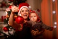 Happy mother showing Christmas ball to baby