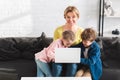 happy mother smiling at camera while using laptop with children Royalty Free Stock Photo