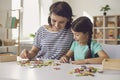 Happy mother and smiling daughter sitting and collecting puzzle together at home Royalty Free Stock Photo